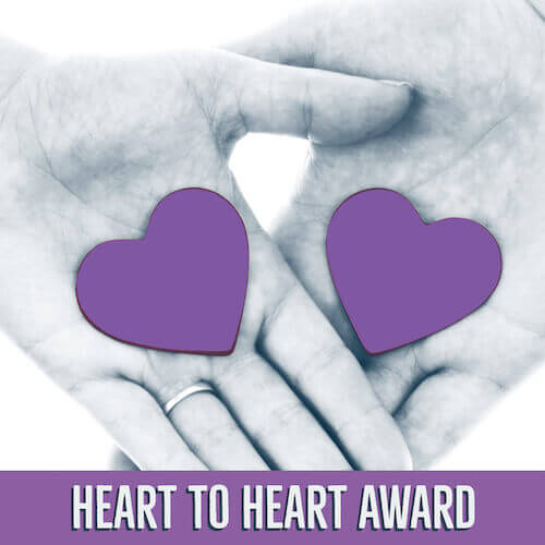 Two hands layed on top of each other with purple hearts in their palms